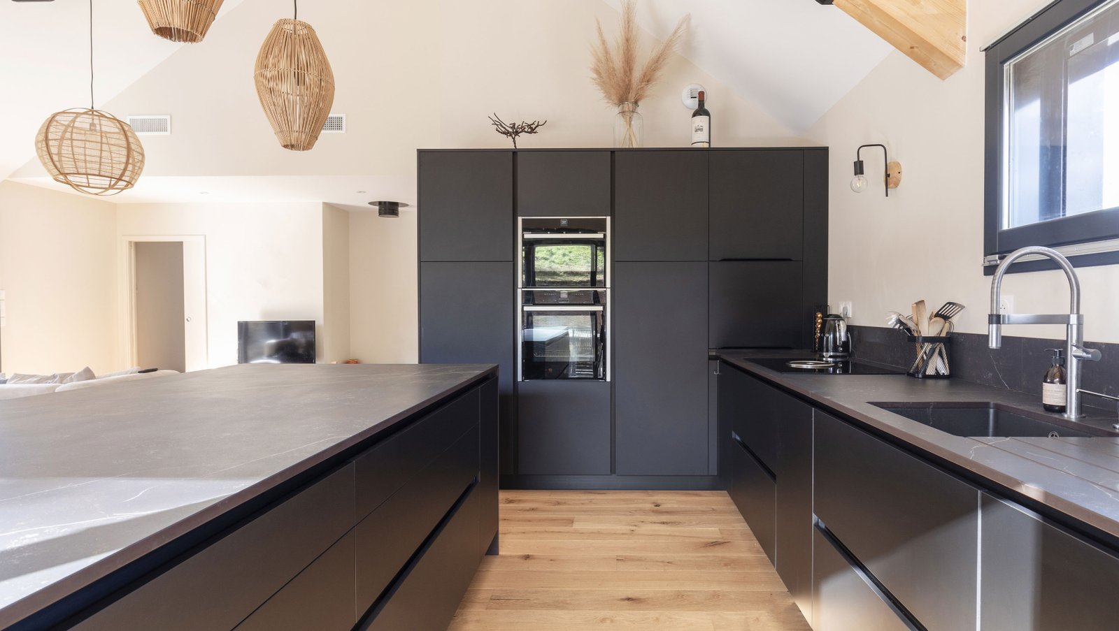 Cuisine ouverte sombre avec îlot et luminaires osier